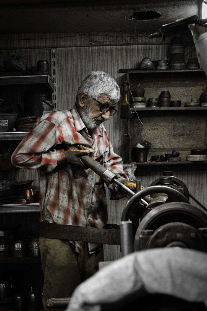 Senior artisan skillfully operates machinery in a rustic workshop setting.